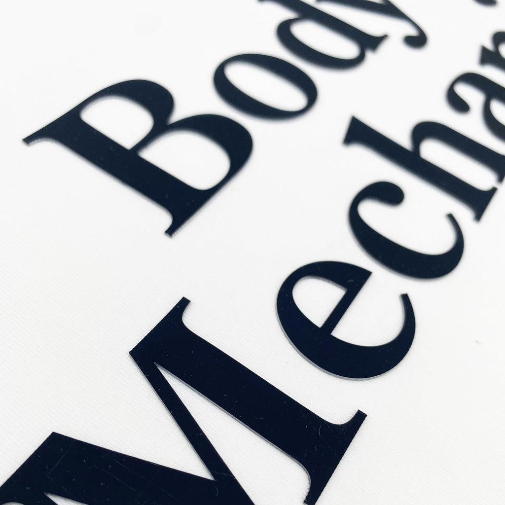 Close-up of 'Body Mechanic' text on a white background