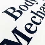 Close-up of 'Body Mechanic' text on a white background