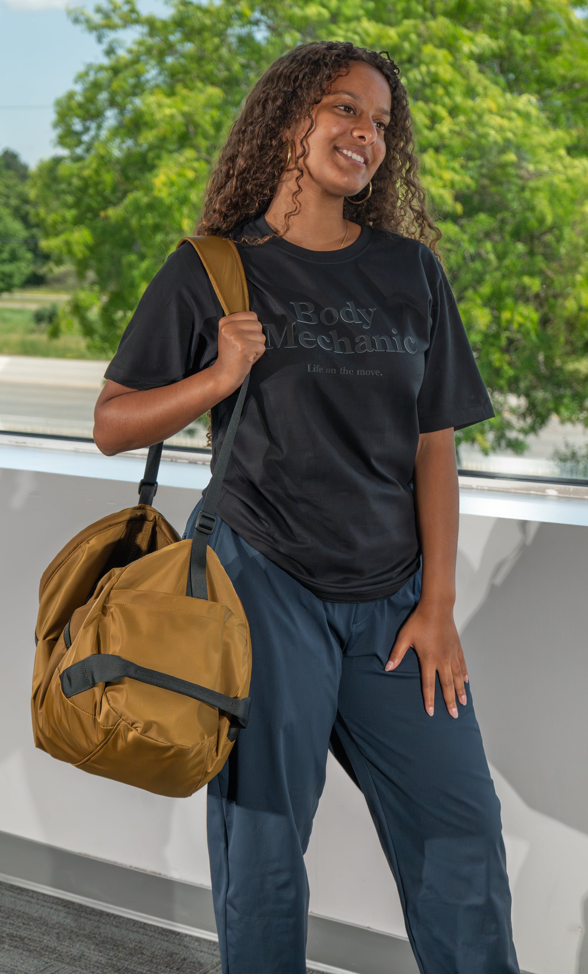 Lady standing with bag with Body Mechanic teeshirt