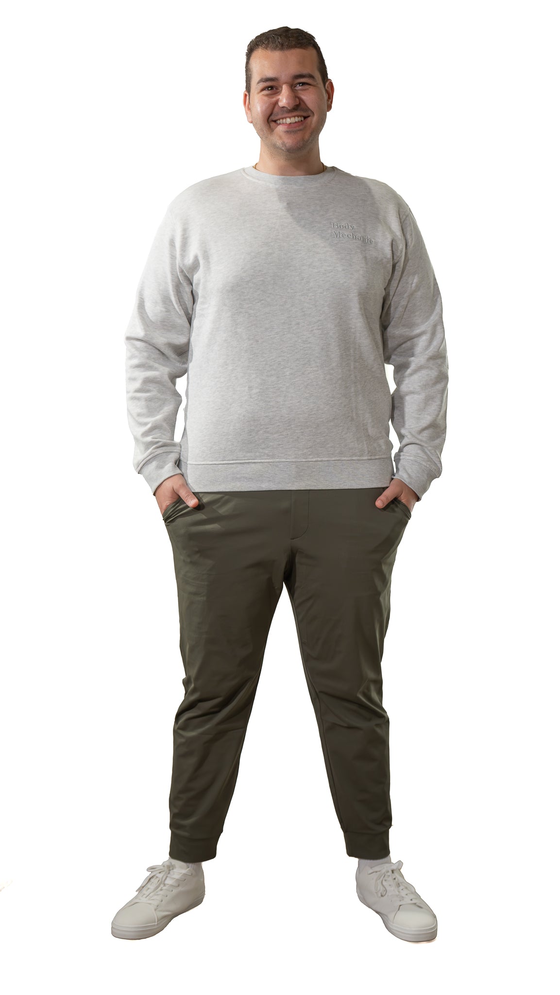 Man wearing a gray Body Mechanic sweater and green pants on a white background