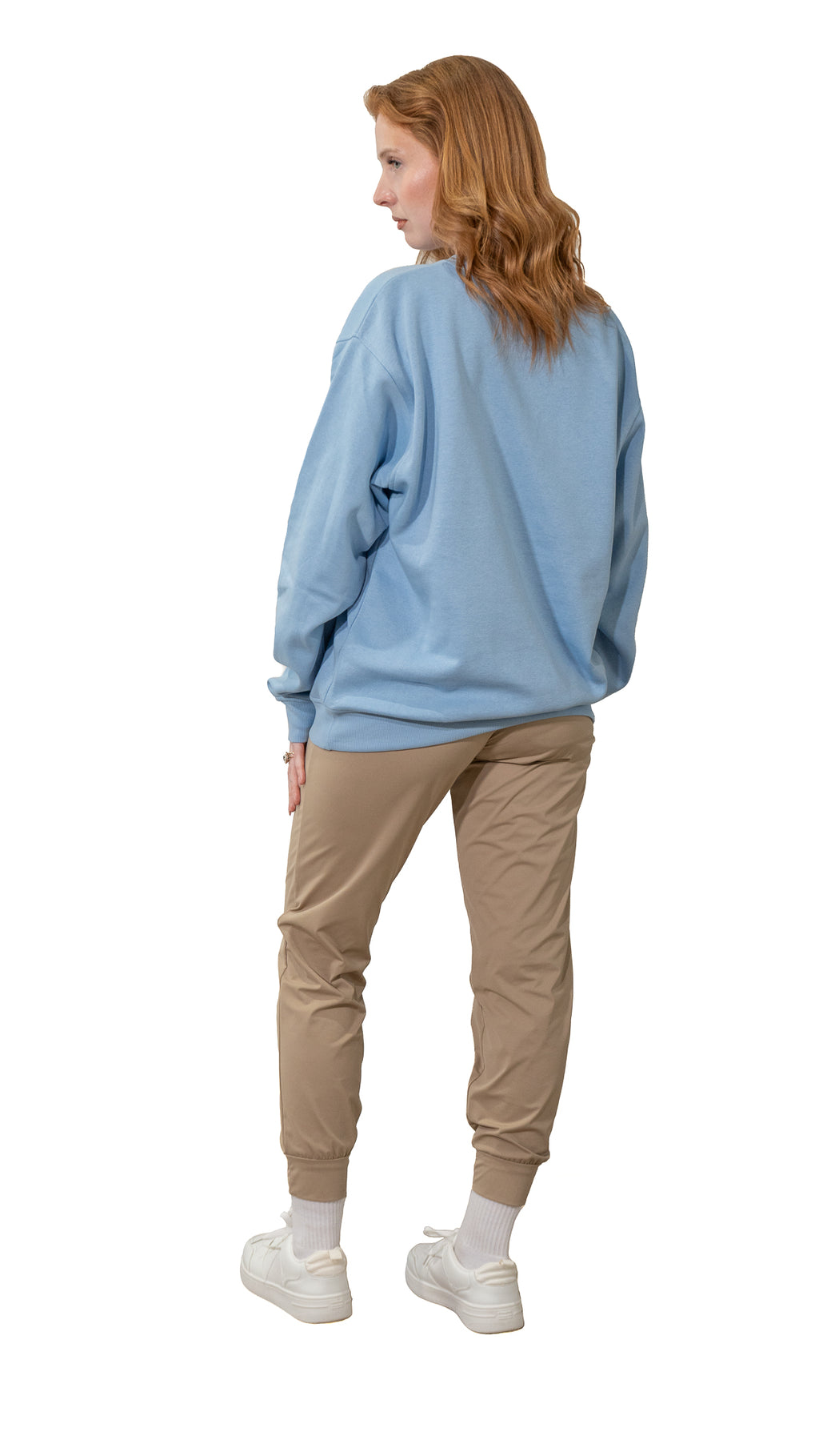 Person wearing a light blue sweatshirt and beige pants on a white background