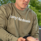 Person wearing a 'Body Mechanic' sweatshirt attending to a client in a clinical setting.